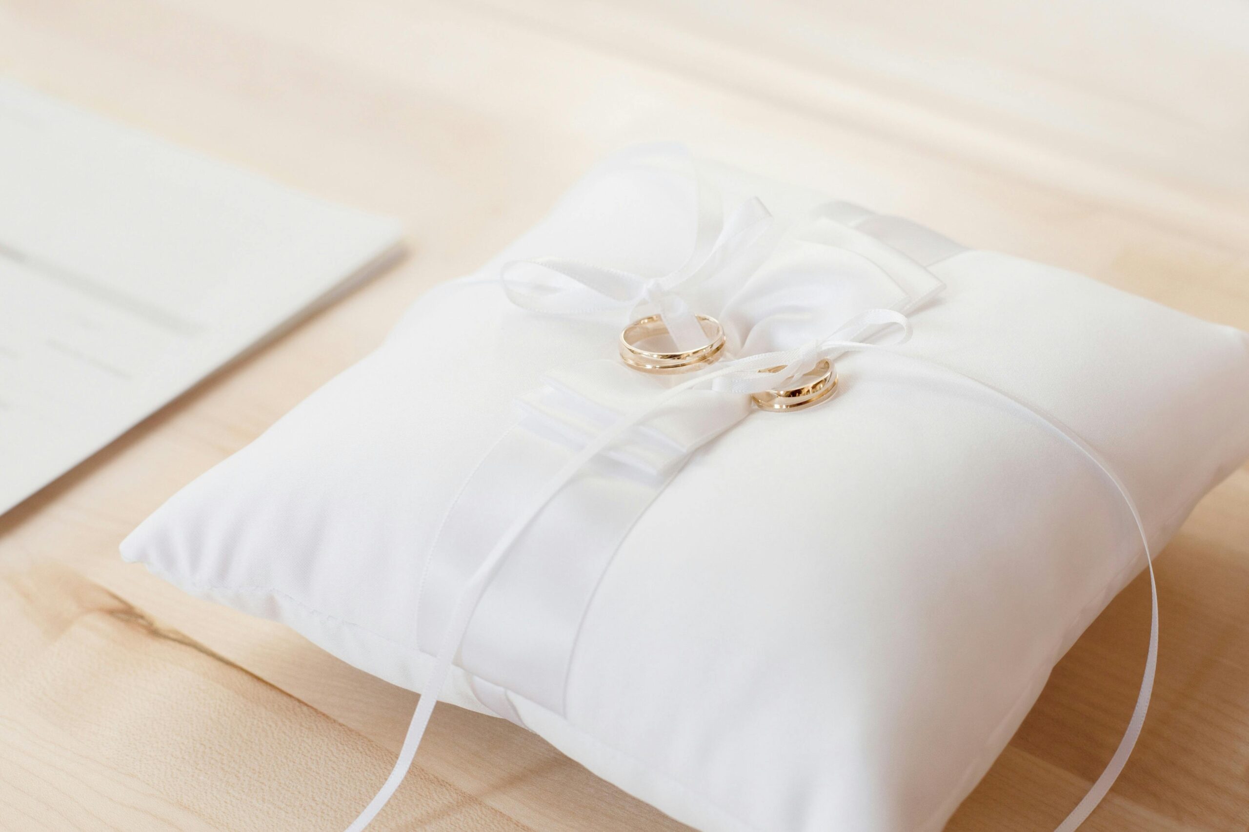 Gold wedding rings elegantly displayed on a white satin pillow, symbolizing love and commitment.